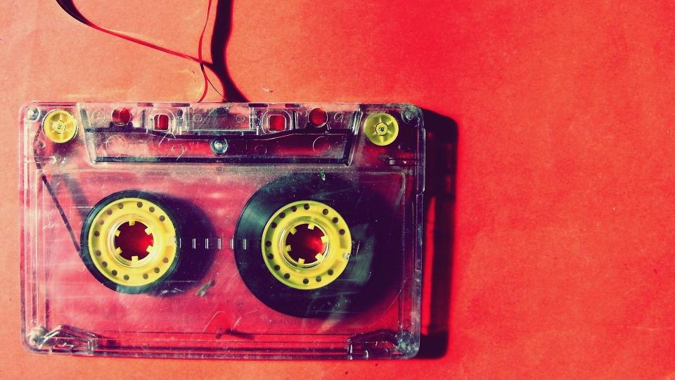 A cassette tape that is unspooling on a red background